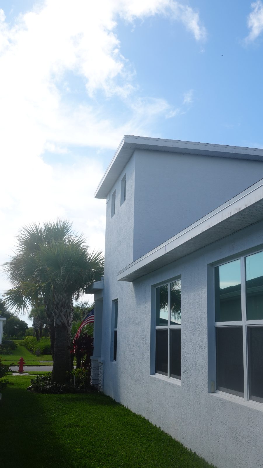 Side elevation: two-story block rising over the one-story roof; run-off streaking on the lower fascia and soffit