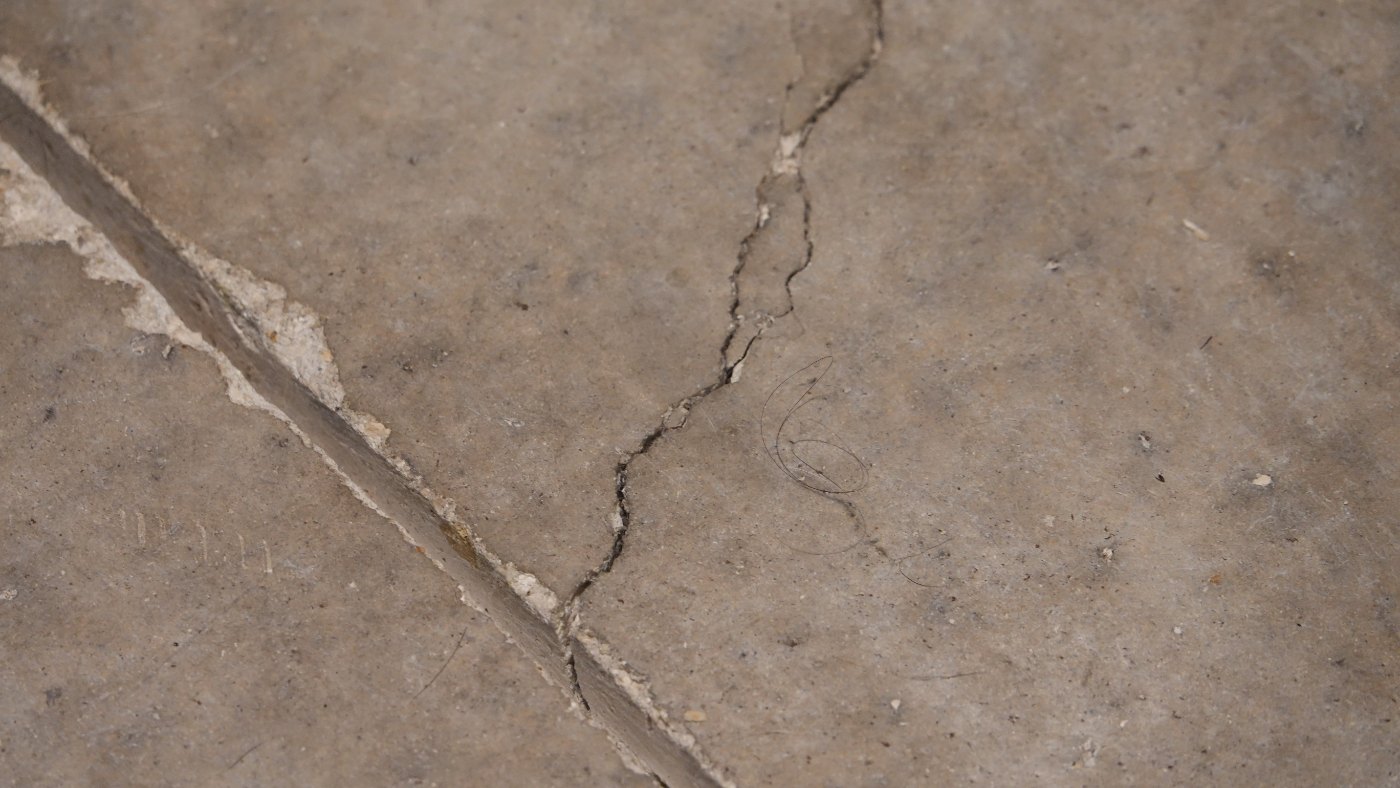 Garage slab: crack running into the sawn control joint, whose edge is spalled