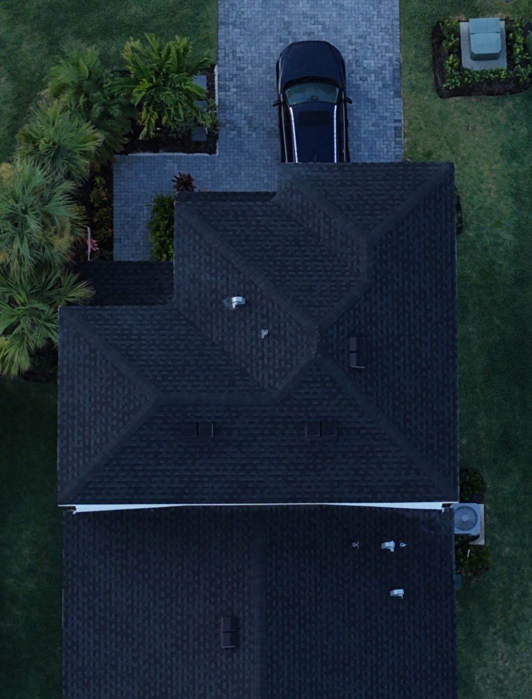 Drone, top-down: front half of the house; two-story roof terminating onto the one-story roof at a headwall with no gutter
